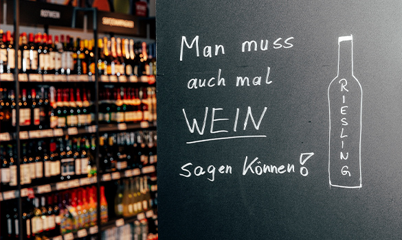 Schild mit dem Titel "Man muss auch mal WEIN sagen können!" vor einem Weinregal in unserem Laden