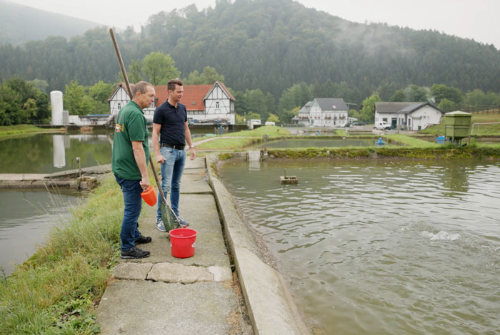 Kay Dreysse und Thomas Rameil vor einem Teich, in dem die Forellen aufwachsen, die du frisch direkt in der Nähe in Siegen kaufen kannst