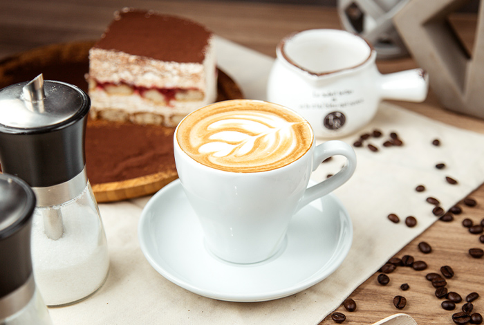 Latte Macchiato mit Kuchen im Hintergrund aus Kaffee aus unserem Angebot