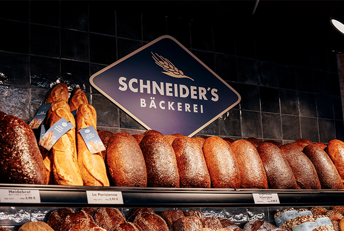 Logo von Schneider's Bäckerei direkt über einem Regal mit Brotlaiben