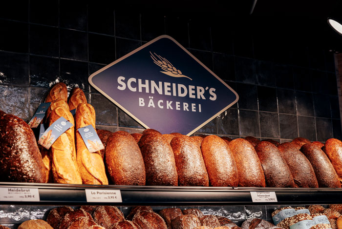 Ein Regal voller Brote mit dem Schneider's Bäckerei Logo im Hintergrund